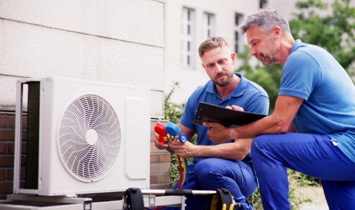 HVAC technicians reviewing an outdoor air conditioning unit in Draper, UT