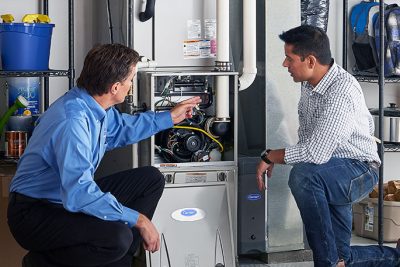 65df8c11f3e4c468cbd351a5_furnace repair vs replacement – Copy HVAC technician explaining furnace repair and maintenance to a homeowner in Draper, UT